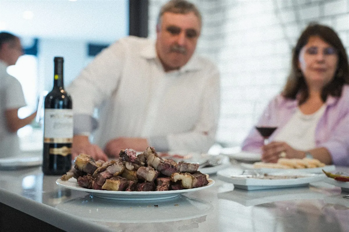 Grupo de amigos cenando carne a la brasa en la isla de la cocina de Sala Baccum