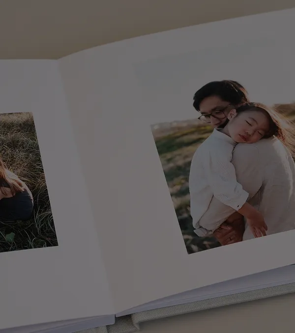 Photo album open showing a daughter sleeping on her father's shoulder outdoors in autumn light.