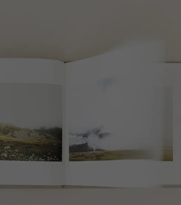 Open book showing photos of a barren landscape with hills and steam rising from the ground.
