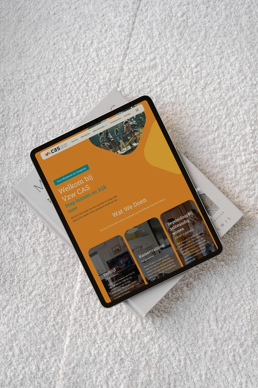 Tablet displaying the VZW CAS website for children and young people, placed on a textured cream armchair.