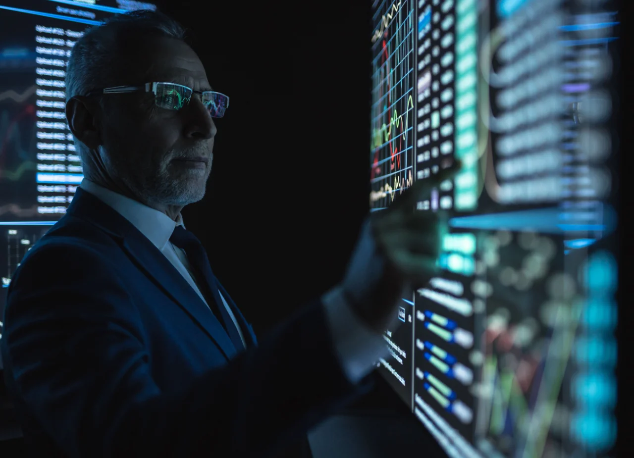 Investment professional reviewing investor relations reporting data and portfolio performance metrics across multiple screens.