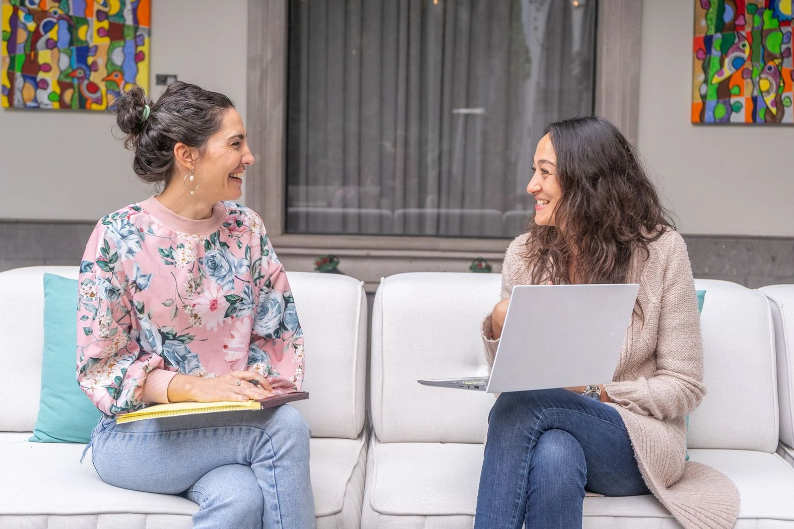 Group enjoying outdoor dinner, candles glowing, laughter, casual attire, evening ambiance, shared meal, wine bottles on table.