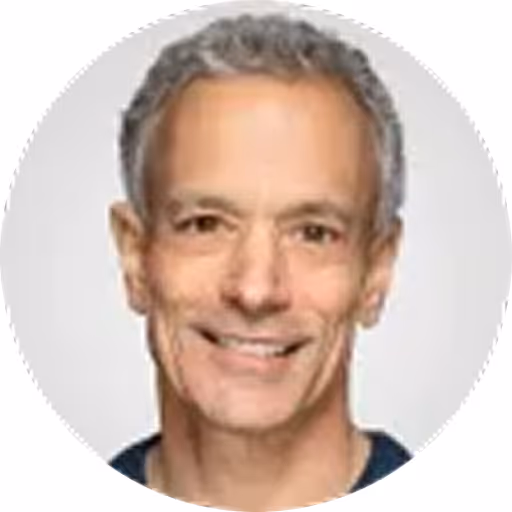 Portrait of a middle-aged man with short gray hair smiling against a light background.