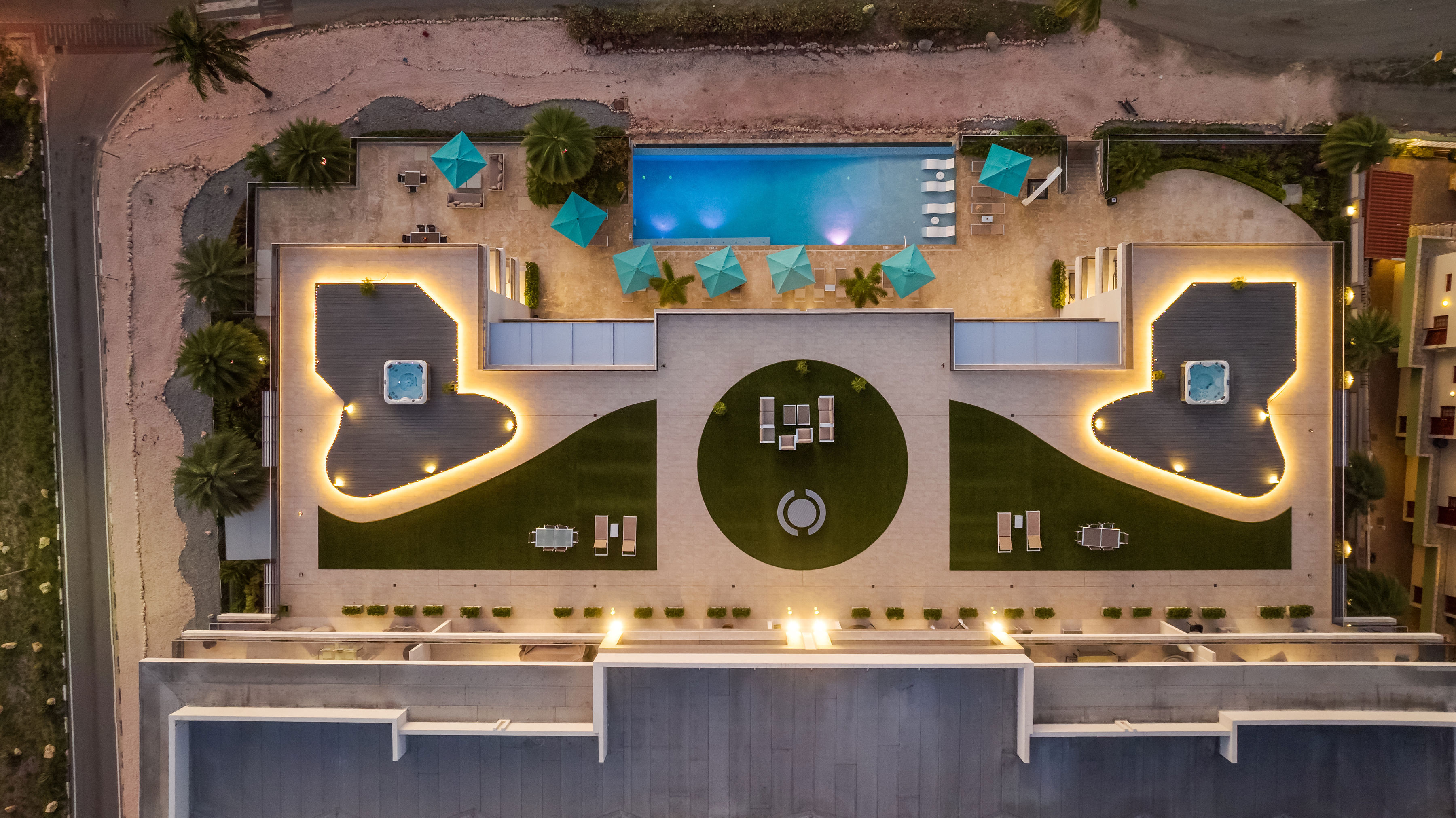 Aerial night view of the O Condominium rooftop pool deck on Eagle Beach, Aruba