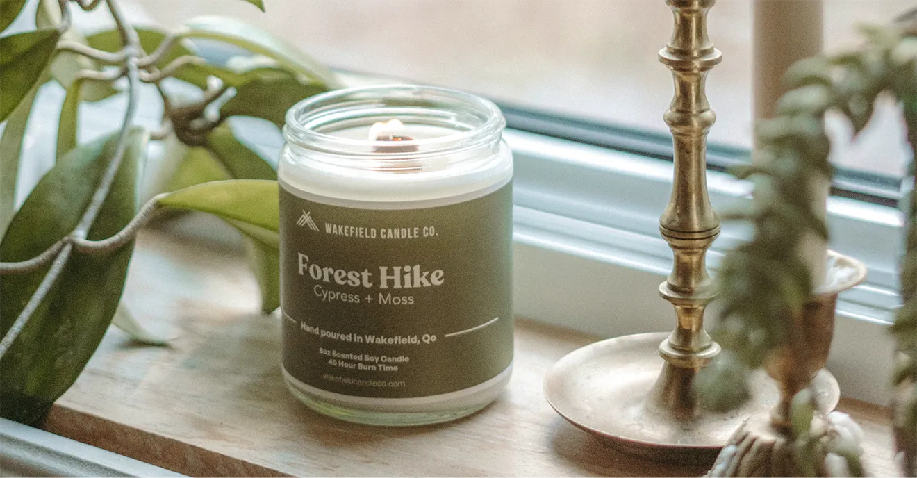 Wakefield Candle Co. Forest Hike candle product photo featuring natural wood and foliage styling.
