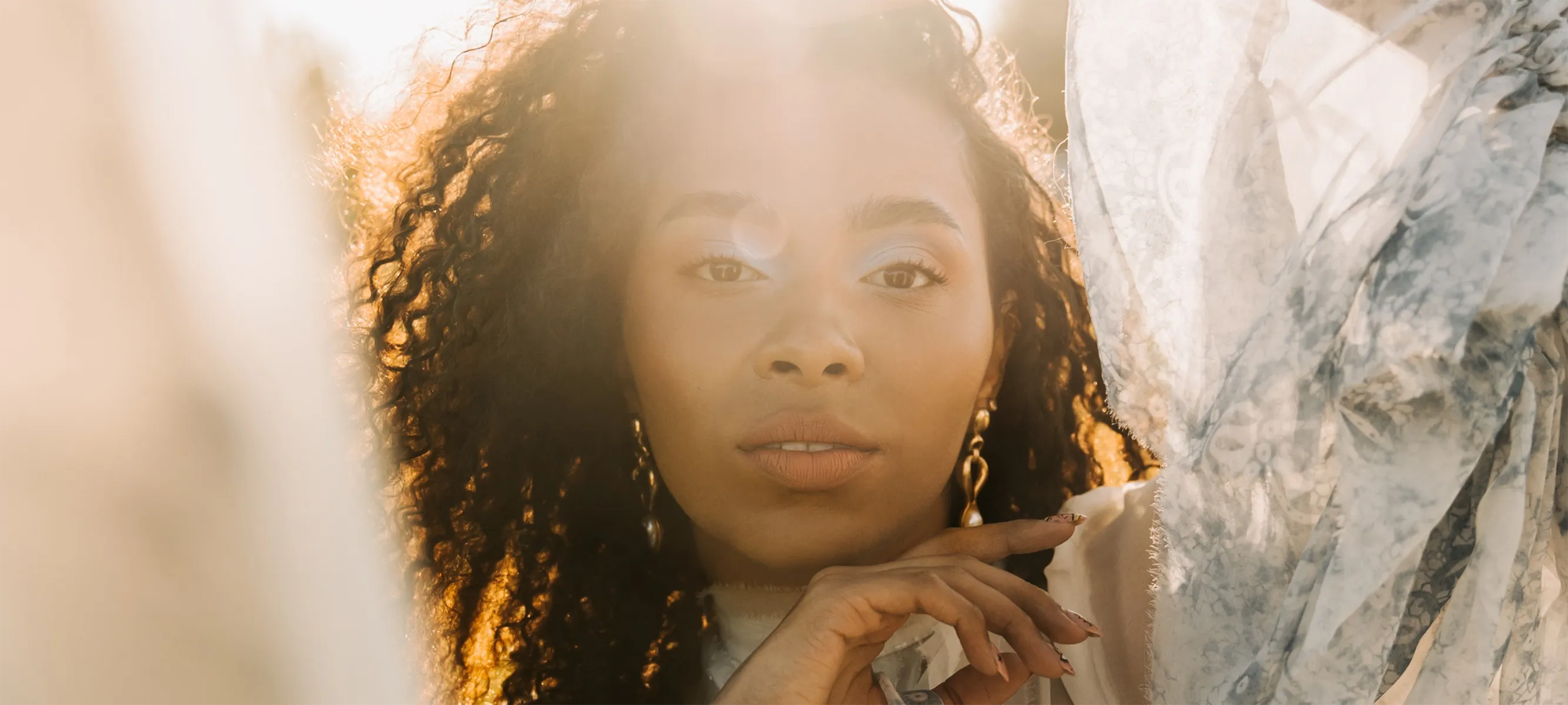 Ambiance Botanique brand photography featuring a woman in soft golden-hour light with flowing floral fabric and a luxury lifestyle aesthetic.
