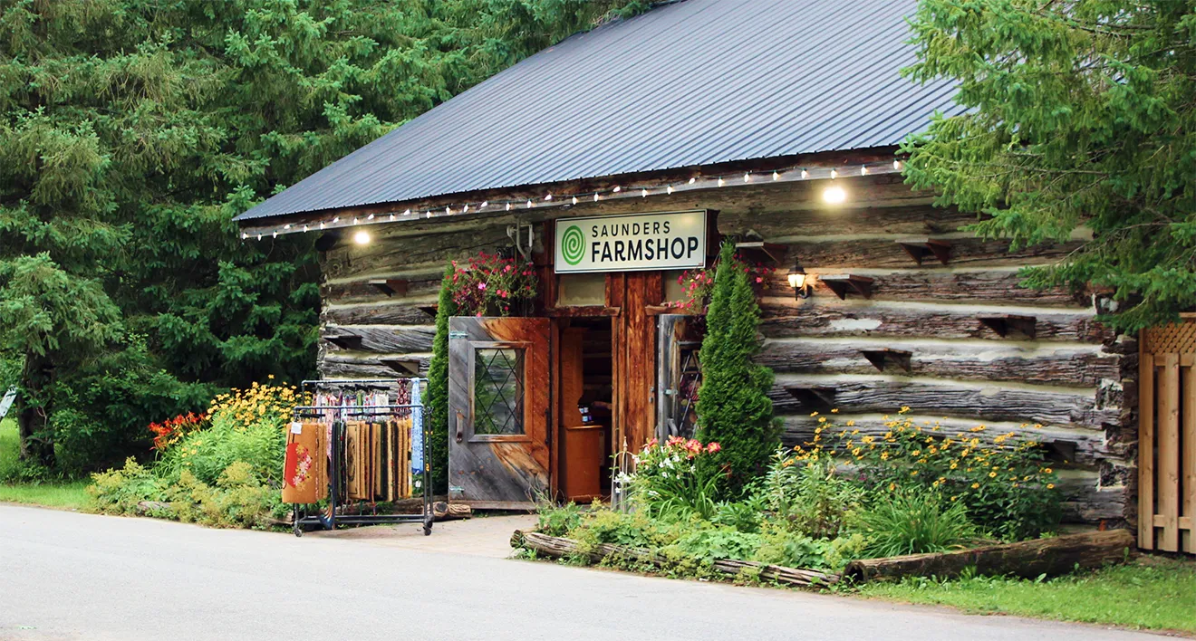Saunders FarmShop storefront featuring rustic log cabin architecture and custom branded signage.
