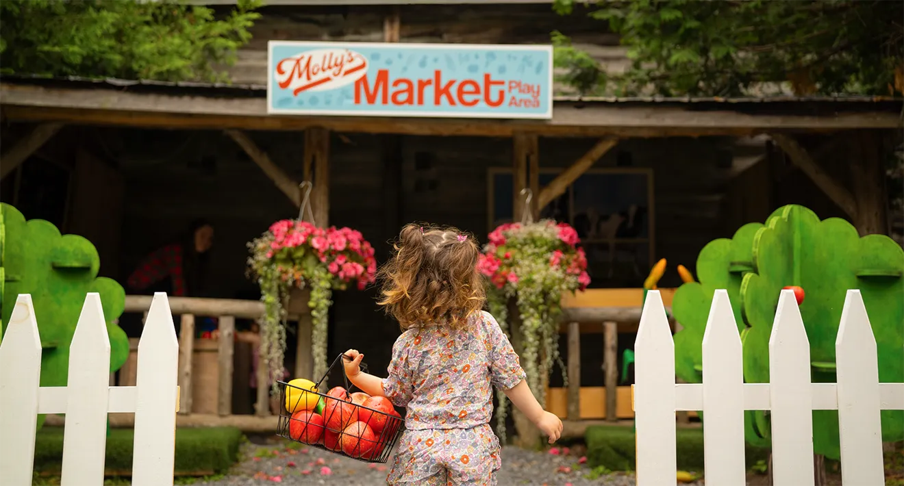 Child entering Molly's Market Play Area under updated script logo sign designed by Hovski Studio.
