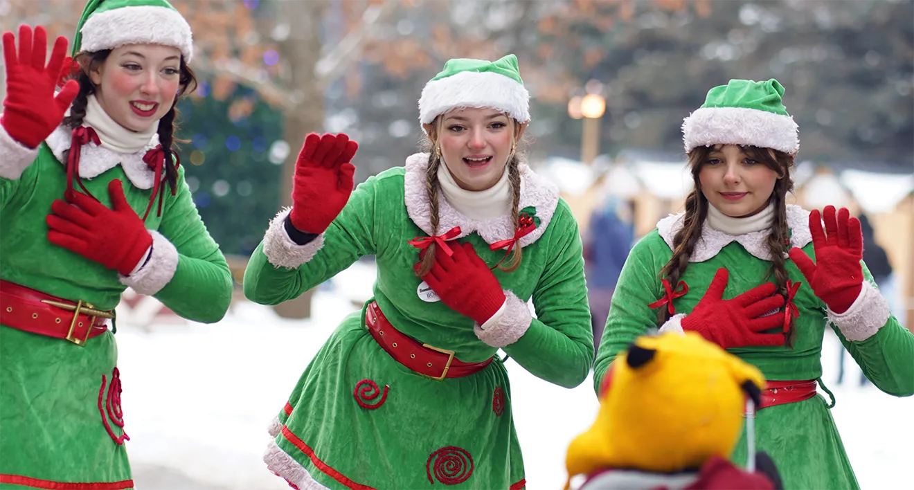 Costumed elf performers waving to a child during Country Christmas at Saunders Farm.