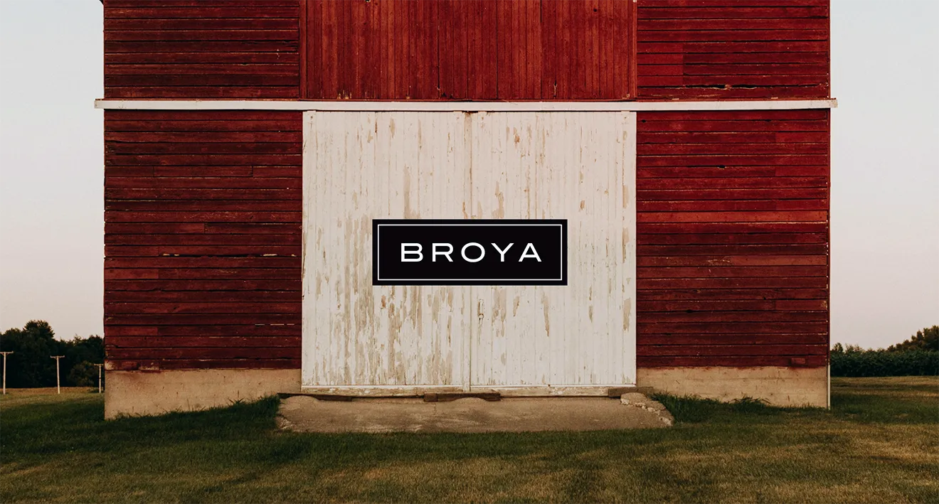 Broya brand logo badge centered over rustic red barn sliding doors.