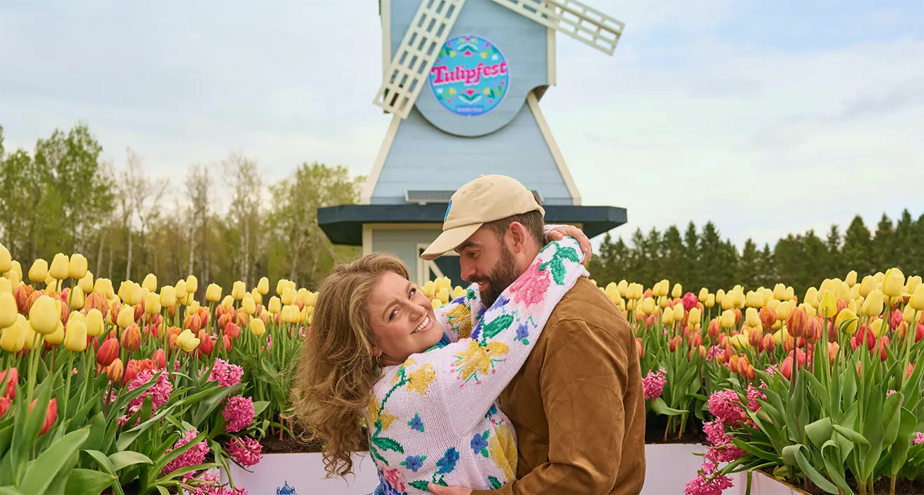 Couple embracing near the custom blue Tulipfest windmill at Saunders Farm, by Kamara Morozuk.