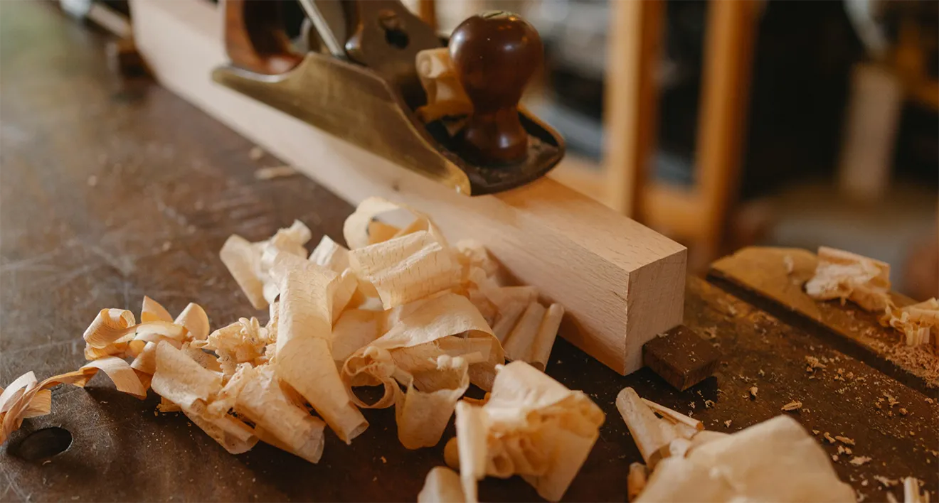 Close-up photography of a vintage woodworking hand plane casting shavings on hardwood.