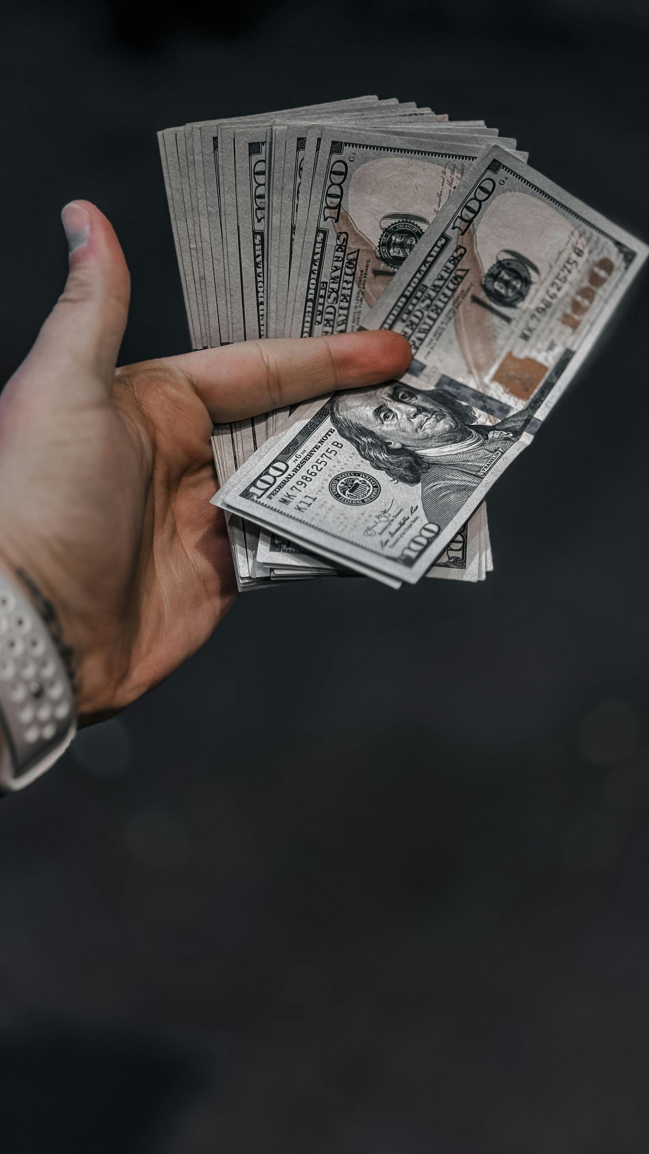 a hand with hundred dollar benjamin franklins
