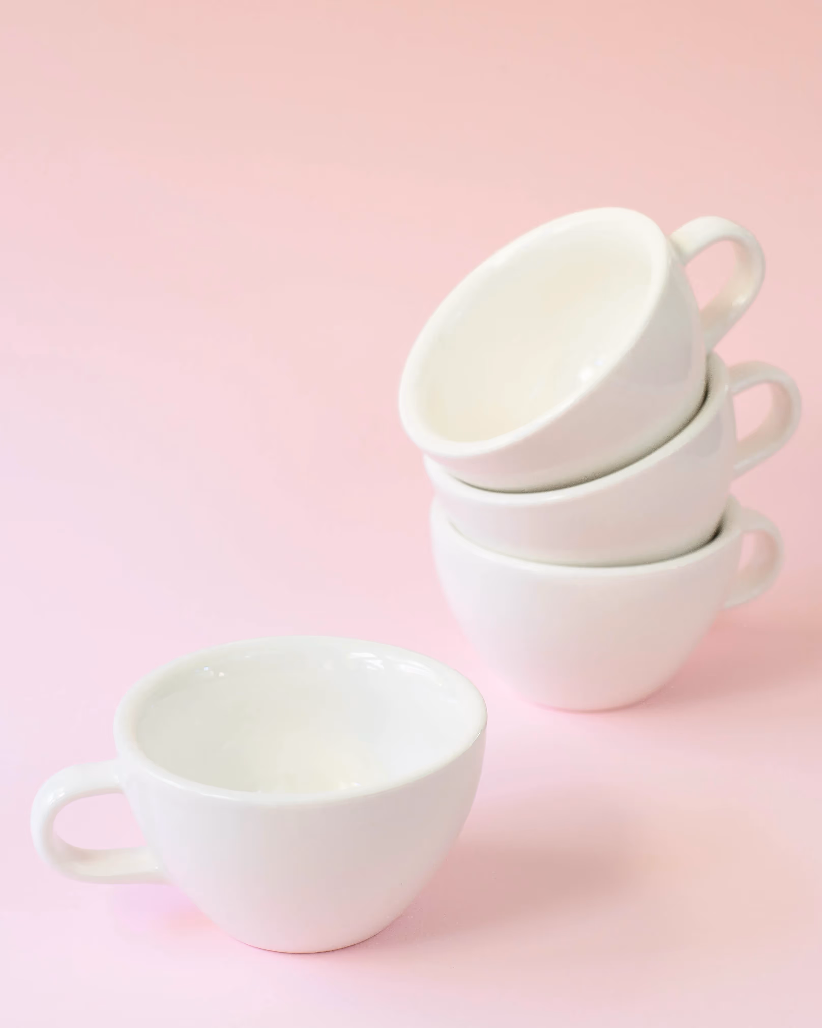 Set of small white coffee cups on pink background