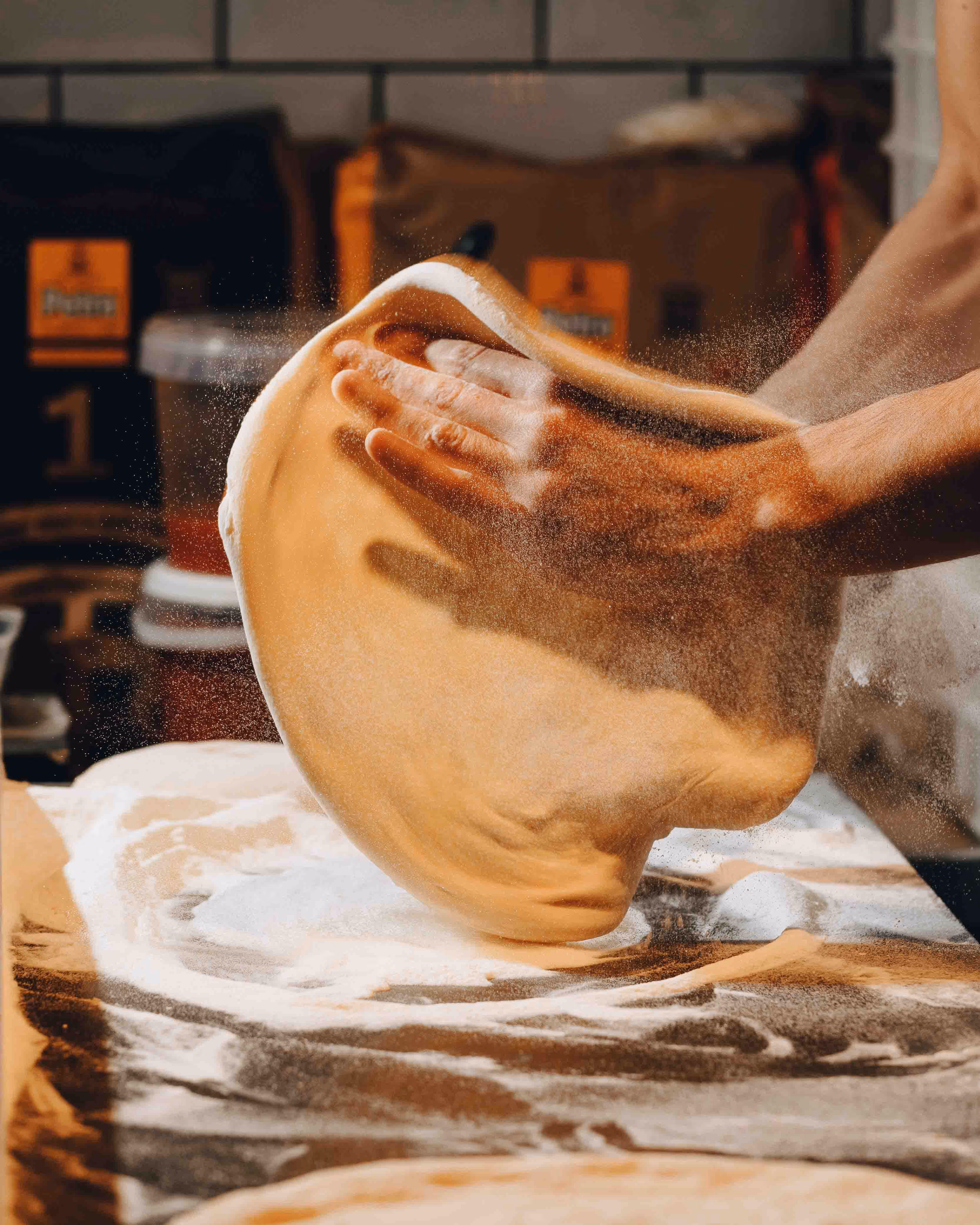 Chef throwing pizza dough, flour in the air