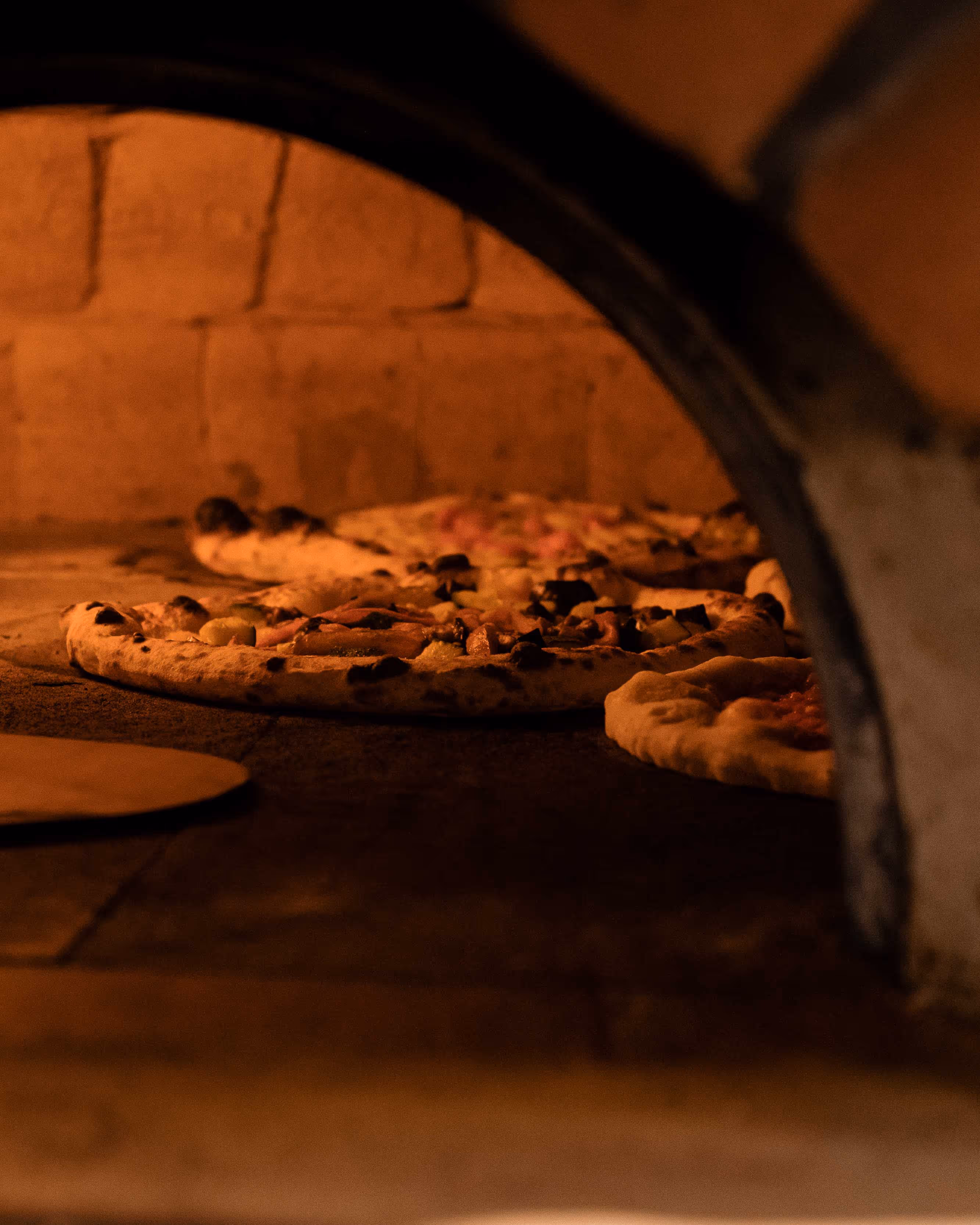 Four pizzas cooking in open wood oven
