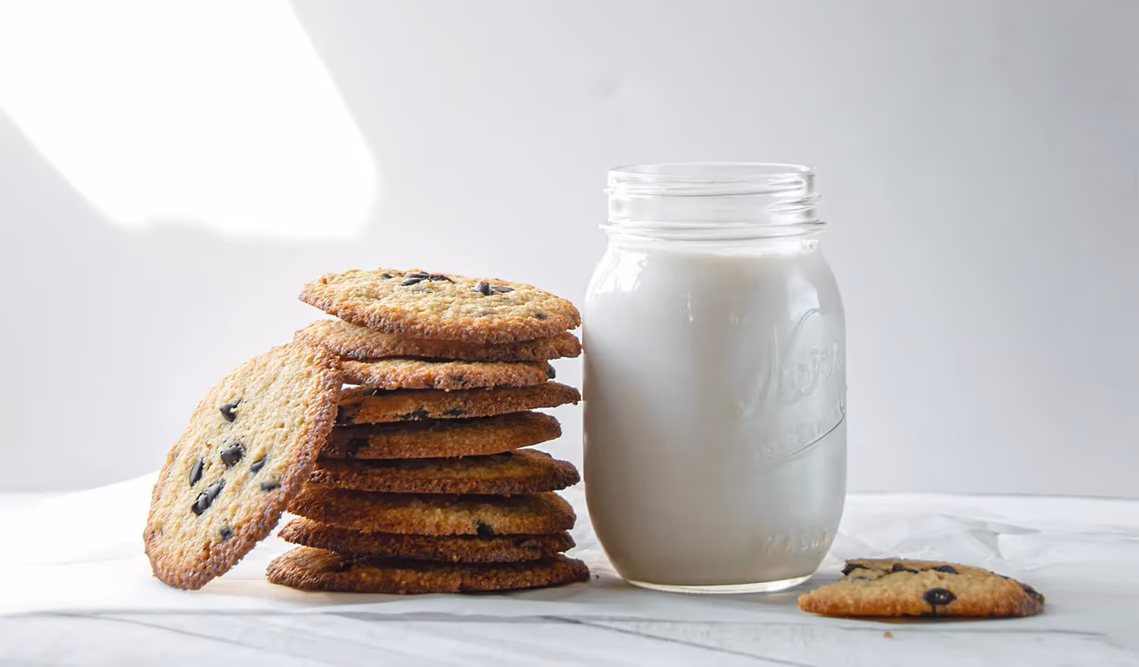 Stack of cookies next to a large glass of milk