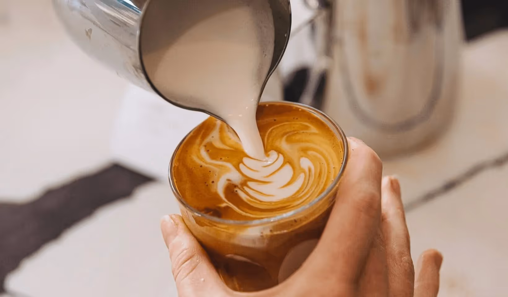 Barista pouring a latte, film grain overlaid
