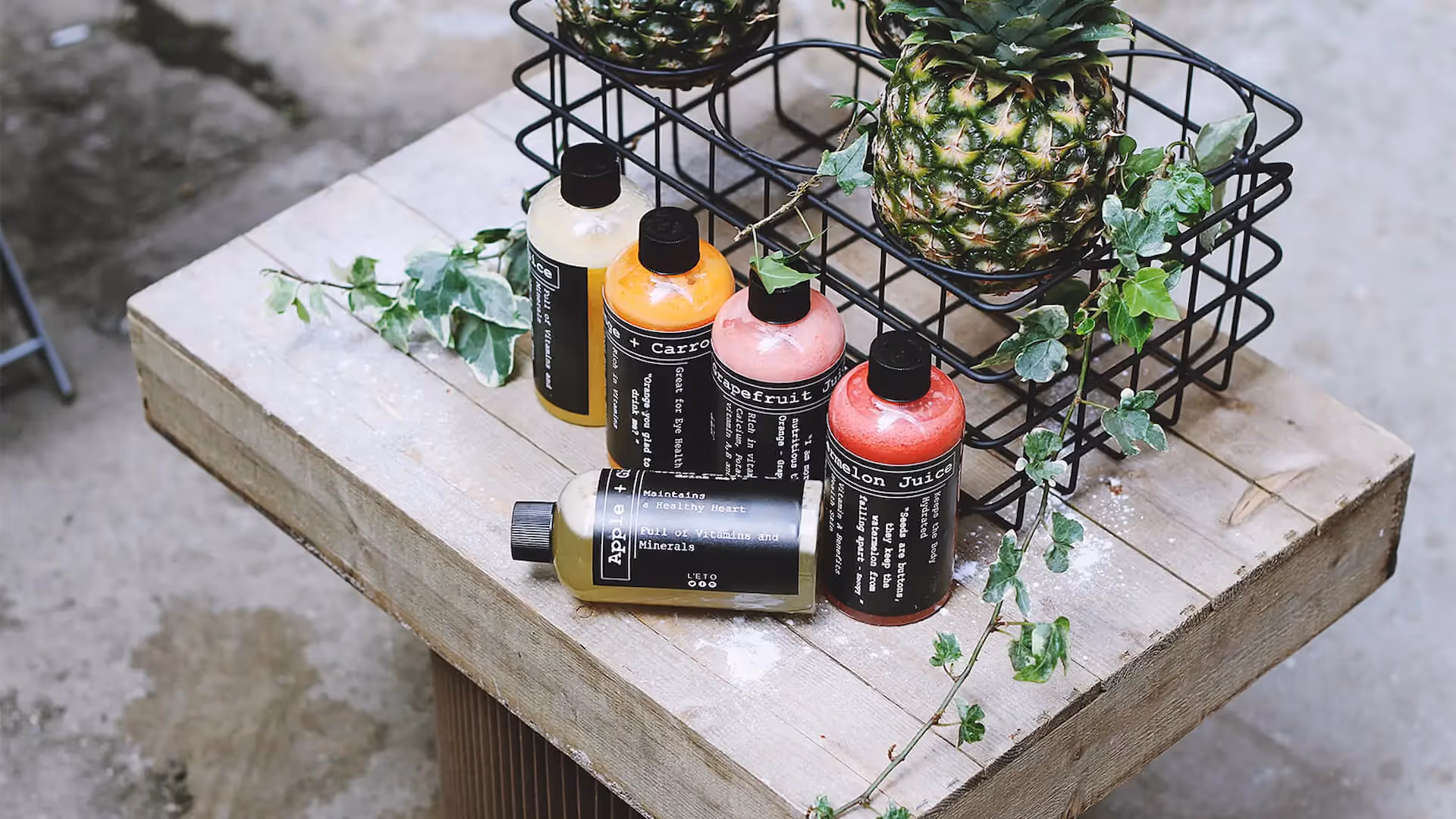 Bottled fruit juices on wooden table with decorative pineapple