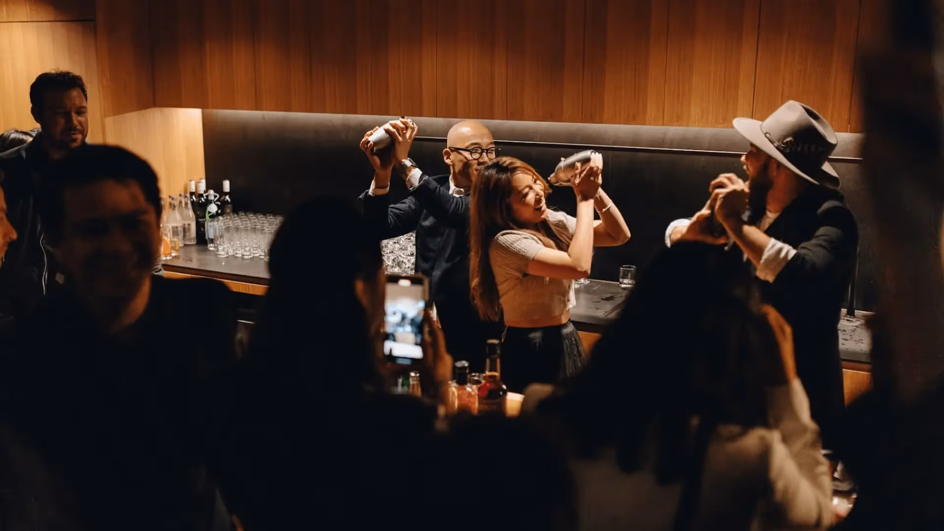 Crowd of happy partiers mixing cocktails in shakers