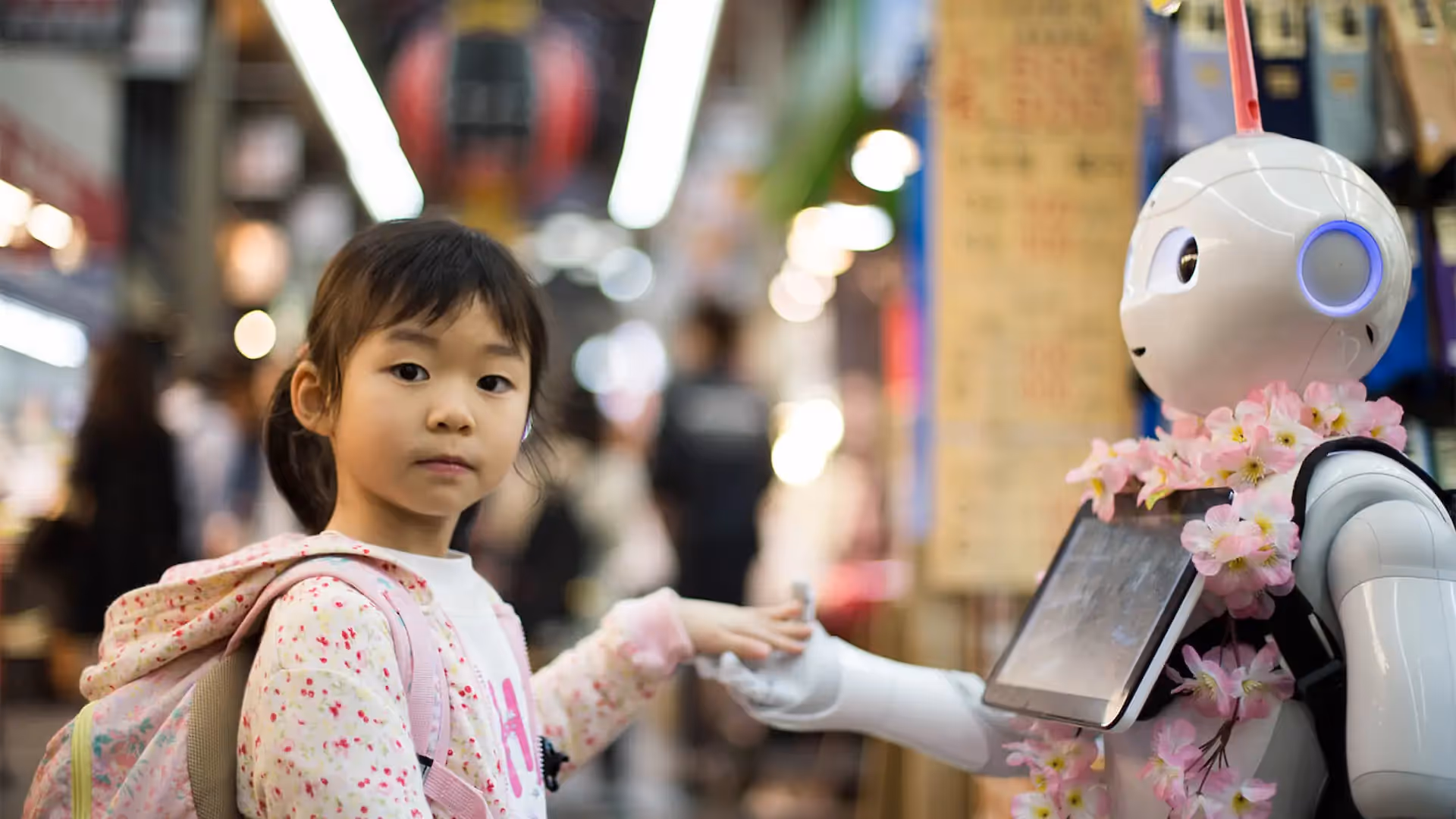 Little asian girl shaking hands with a robot
