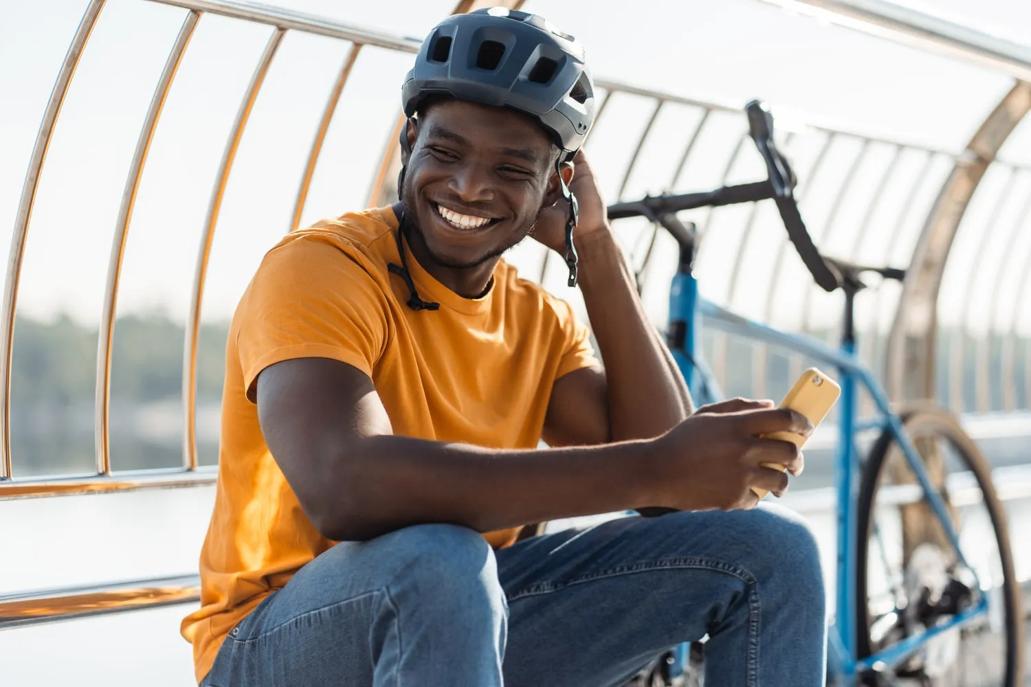 Un homme souriant assis, devant son vélo avec un casque sur la tête