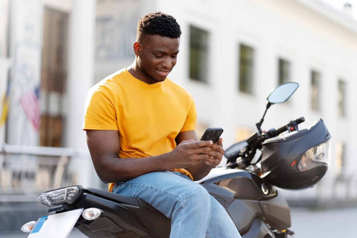 Un homme sur son smartphone, assis sur sa moto