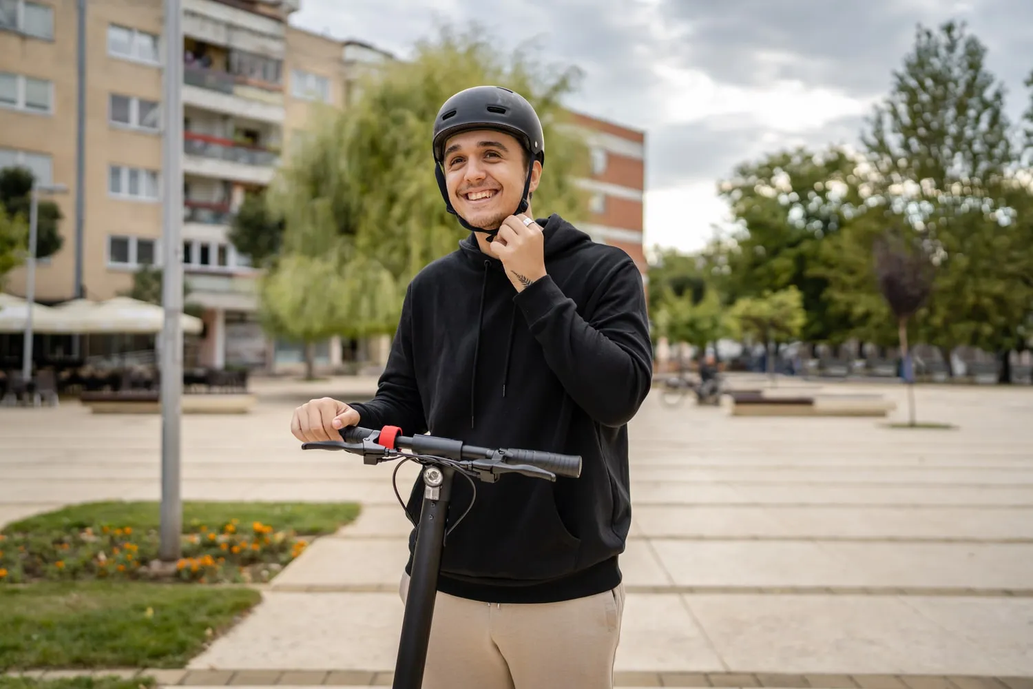 Un jeune homme en trottinette, souriant et portant un casque