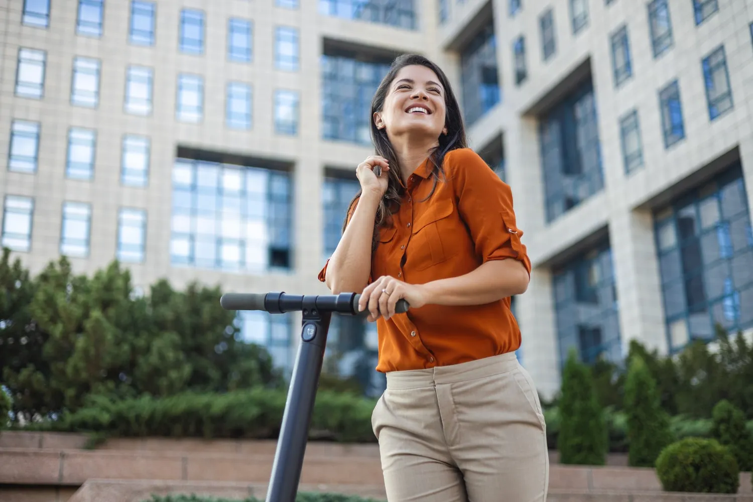 Une femme en train de sourire sur sa trottinette