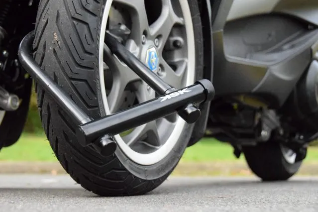 Une roue de moto attachée par un antivol certifié SRA à un poteau