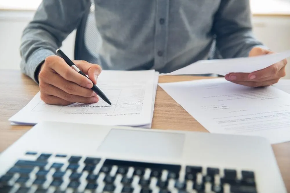 Un homme qui signe des documents sur une table