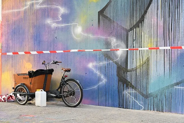 Vélo cargo devant un mur de graffitis