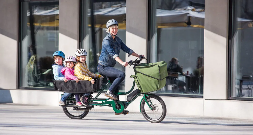 Une femme sur un vélo longtail avec ses enfants à l'arrière