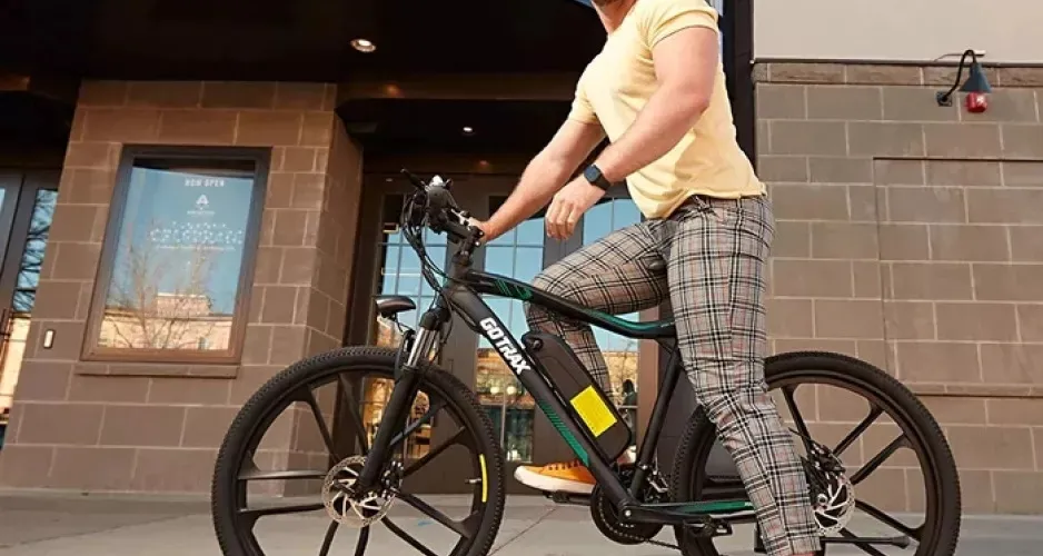 Un homme monté sur un vélo électrique 350 W EBE2 de Gotrax en stationnement devant une porte d'immeuble