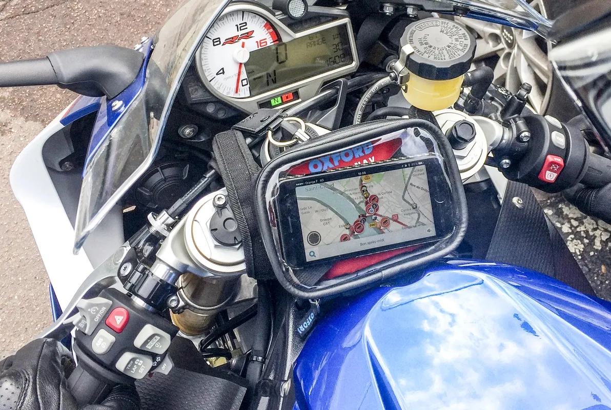 Une moto où sur le devant est accroché un smartphone avec l'application Waze Moto ouverte