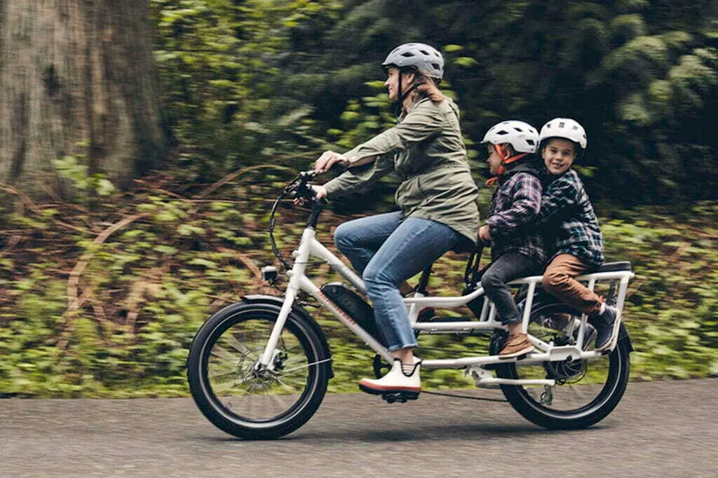Une femme avec ses 2 garçons sur la route avec un vélo longtail