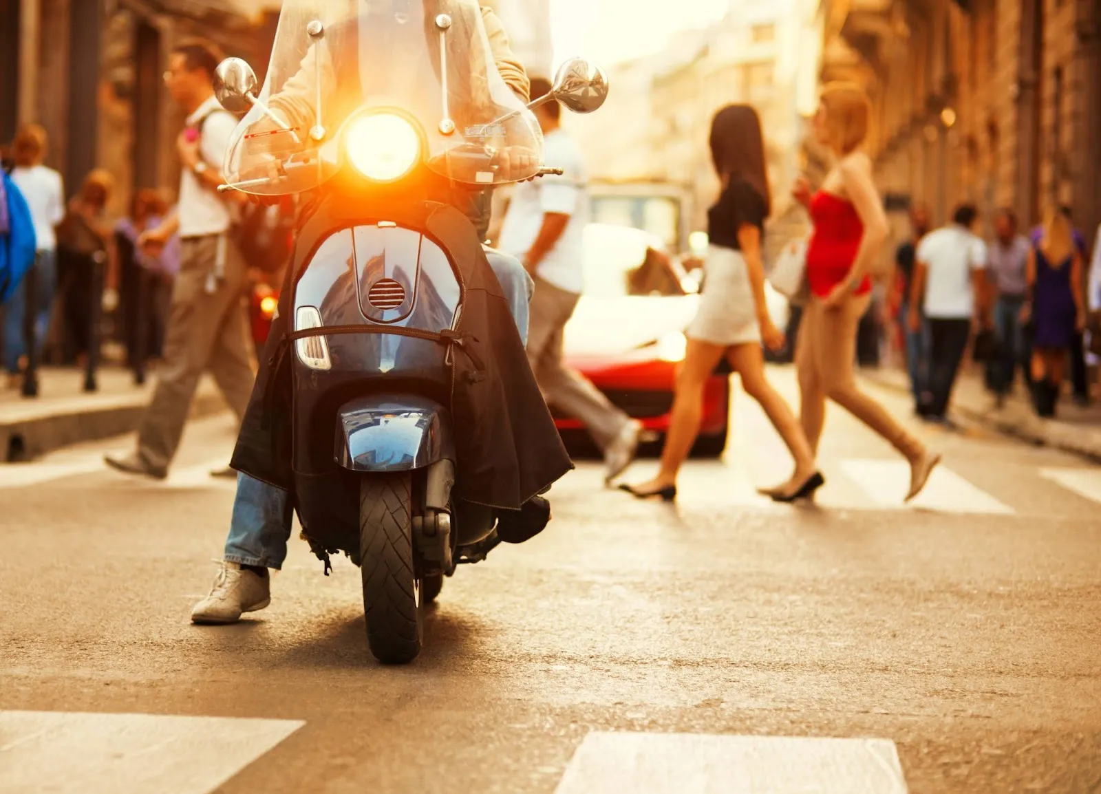 Un homme qui conduit un scooter dans la rue avec des piétons en arrière plan