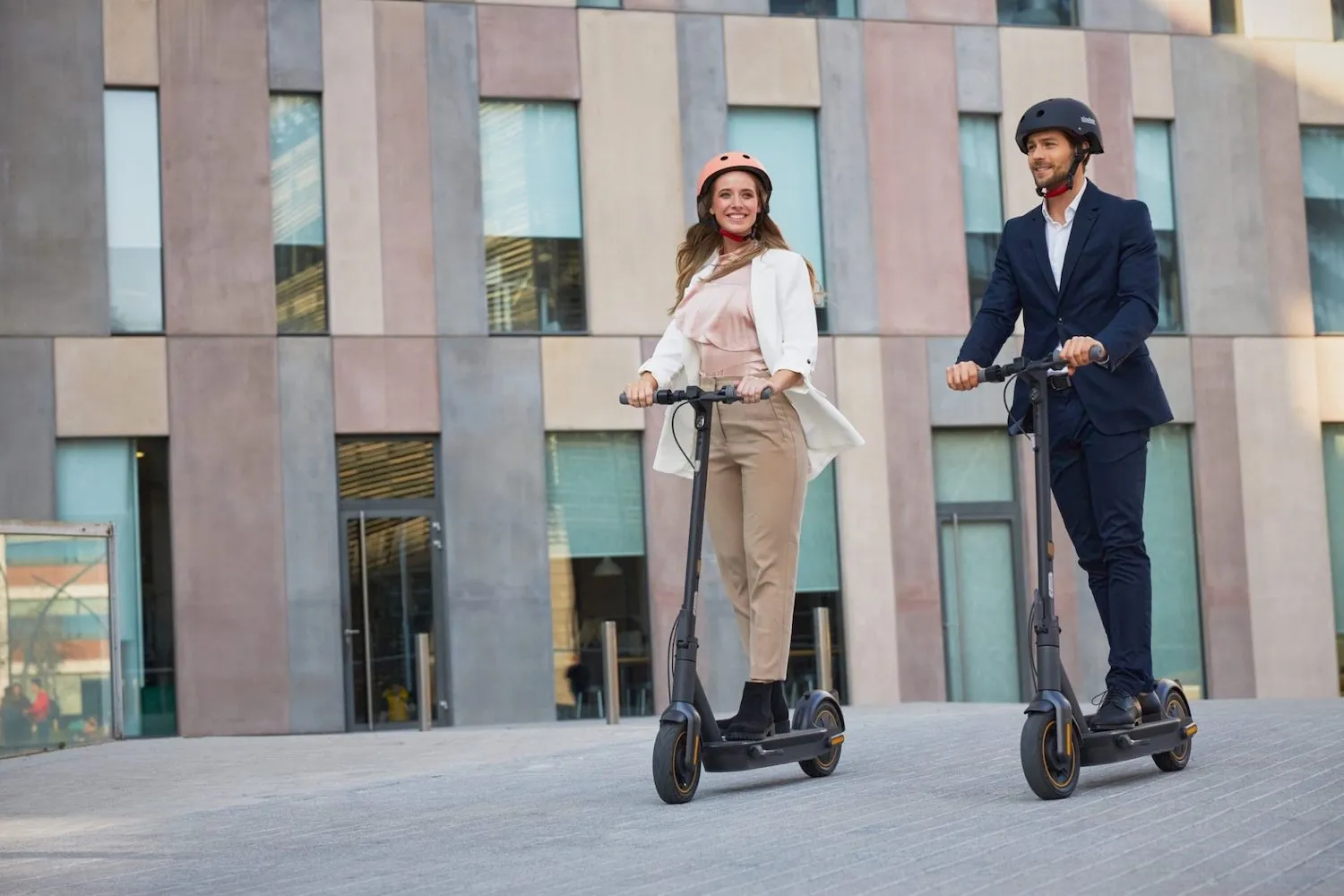 Un couple qui circule avec des trottinettes électriques avec des casques de vélo