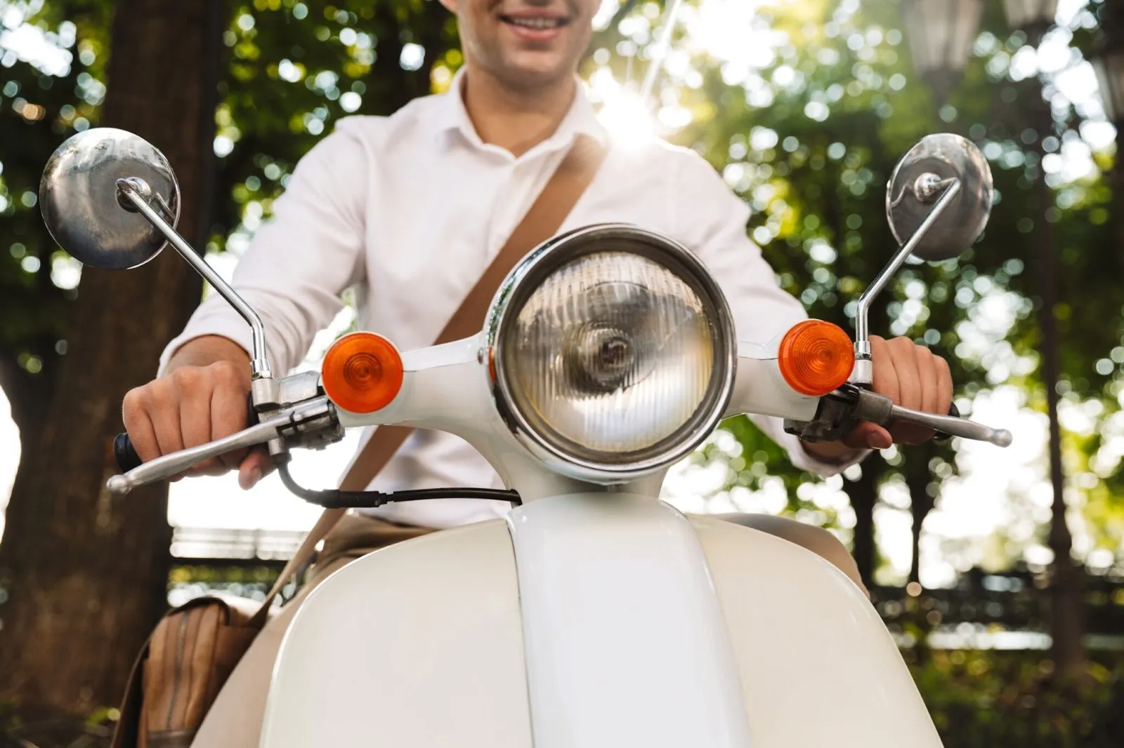 Un homme souriant sur un scooter blanc. 