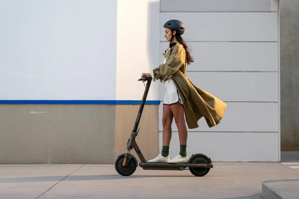 Une femme qui conduit une trottinette électrique dans la rue.