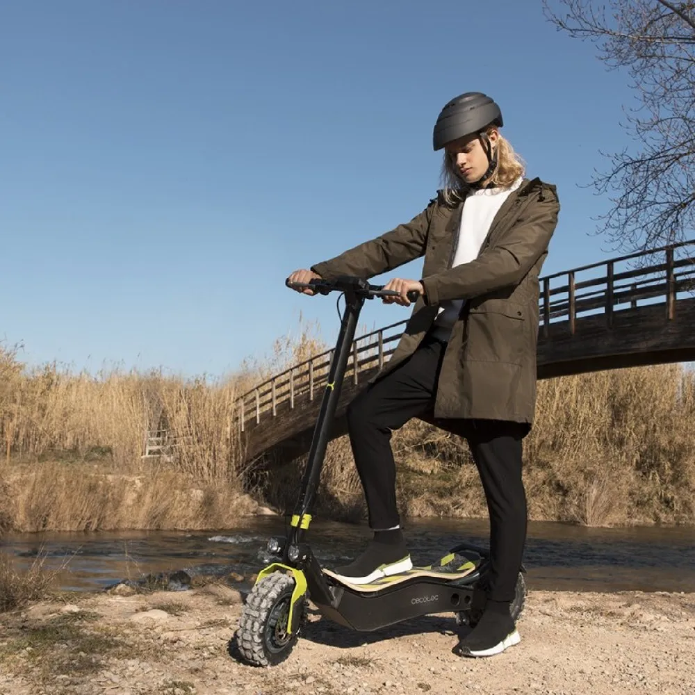 Un jeune homme qui tient la trottinette électrique Cecotec Bongo Z+ Offroad avec un pied sur le deck et un autre au sol