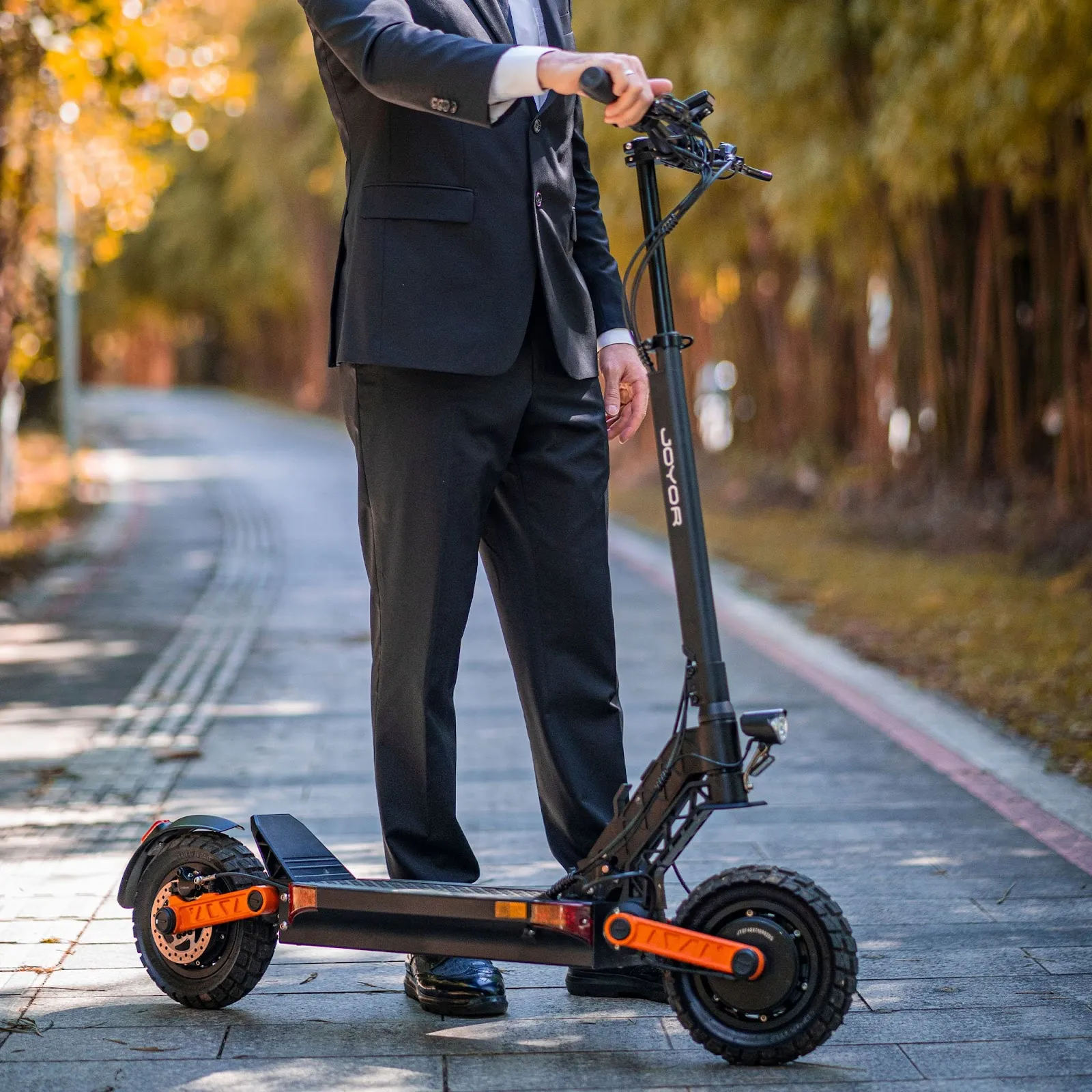 Un homme qui se tient à côté d'un JOYOR S10S noir et orange