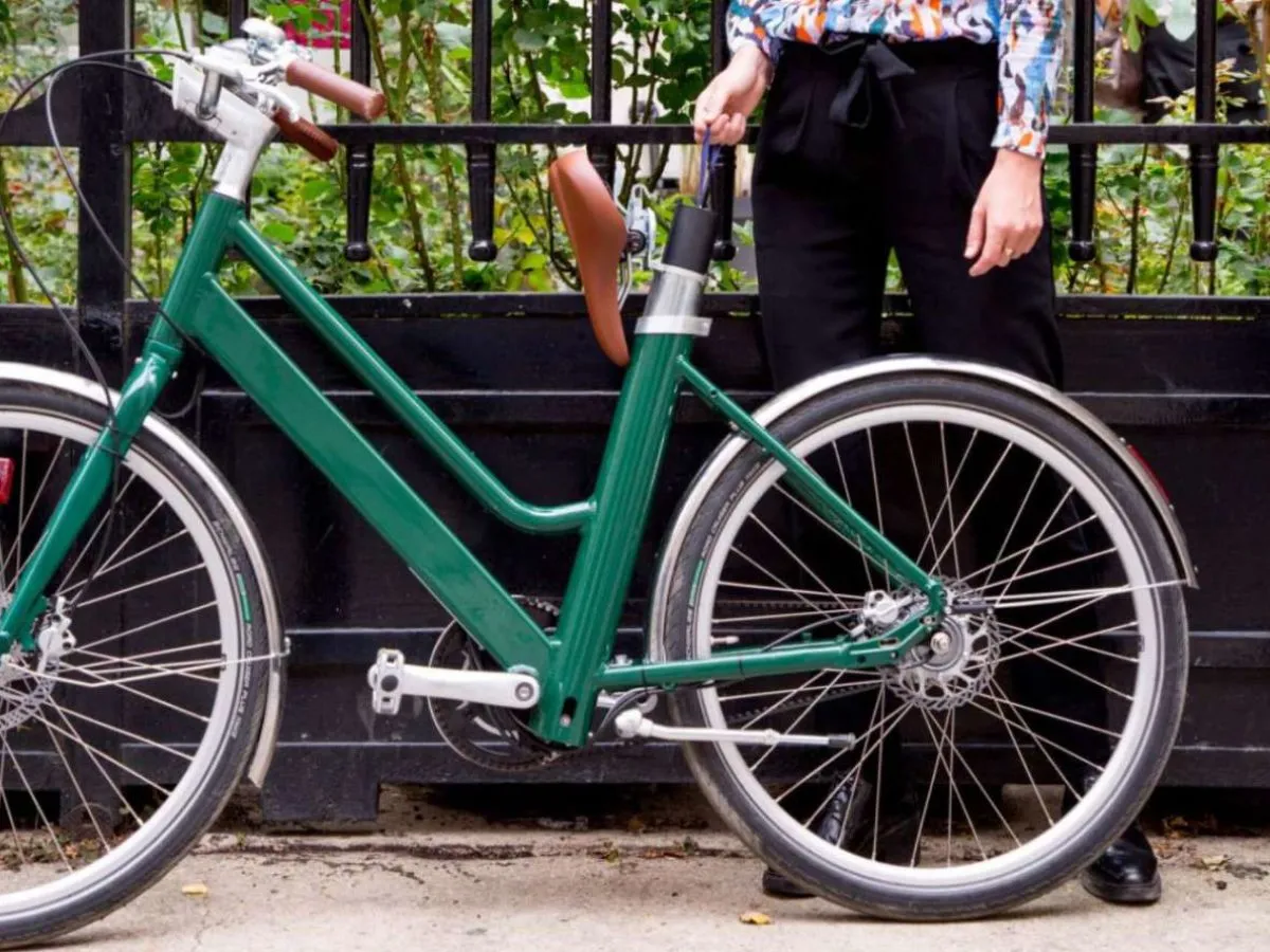 Une femme qui se tient à côté du vélo Legendre Voltaire et qui retire la batterie de son vélo