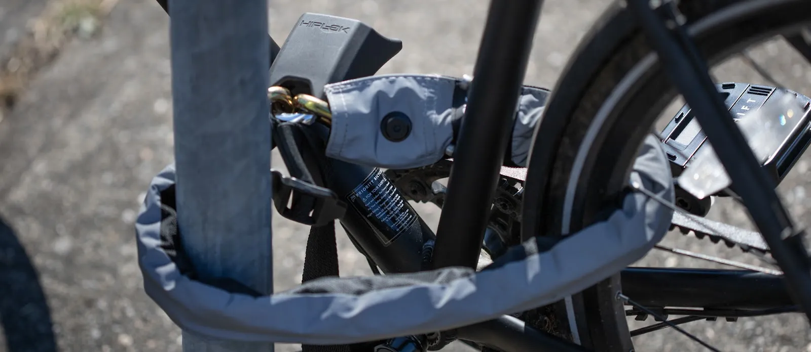 Un vélo attaché à un poto en métal avec le cadena Hiplok Gold Wearable Chain Lock