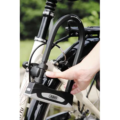 Une main qui tient un cadena Abus 32 Facilo sur un vélo
