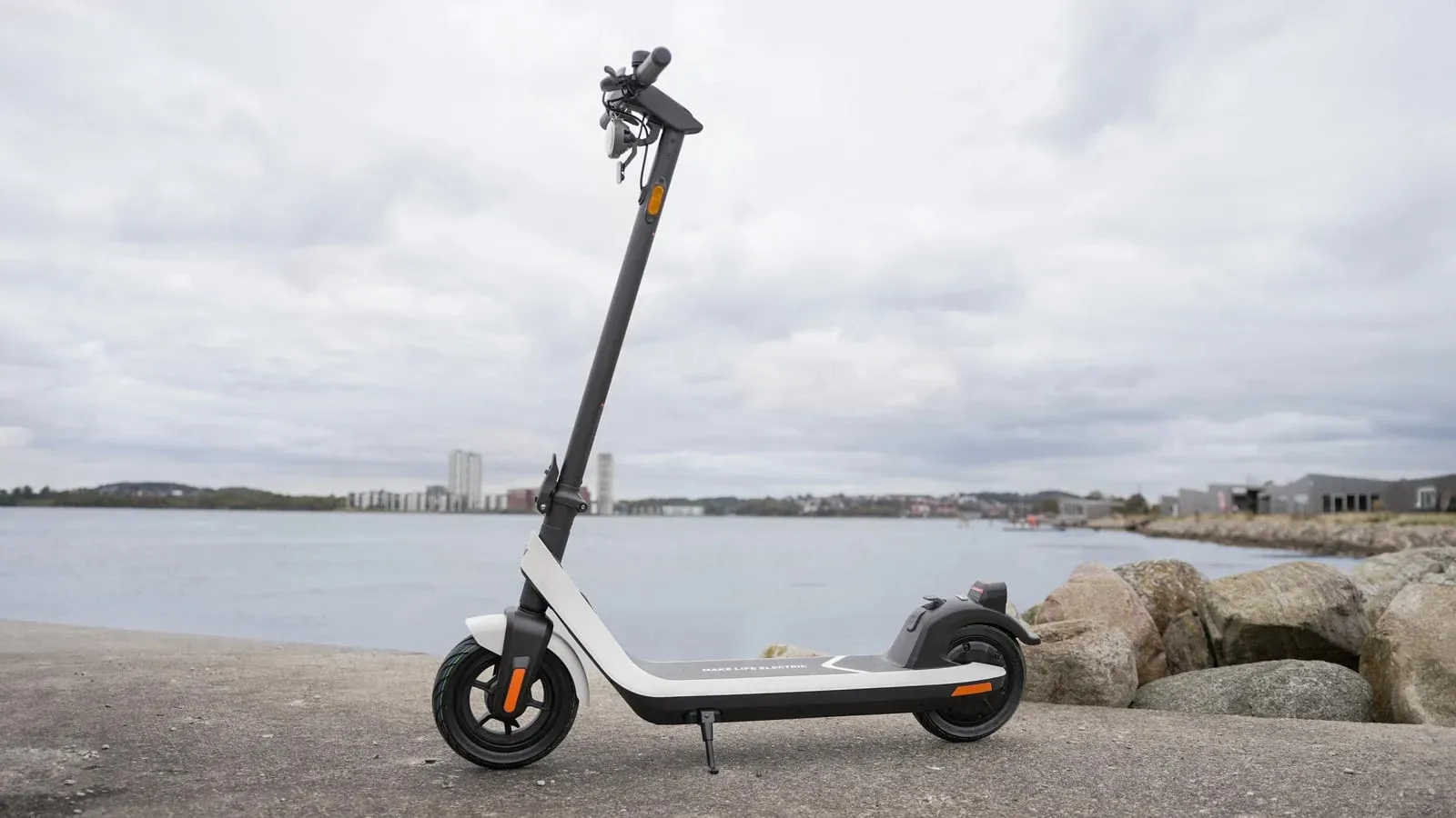 Une trottinette électrique NIU KQi2 Pro garée devant une étendue d'eau.