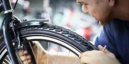 Un homme qui regarde avec attention son pneu de vélo.