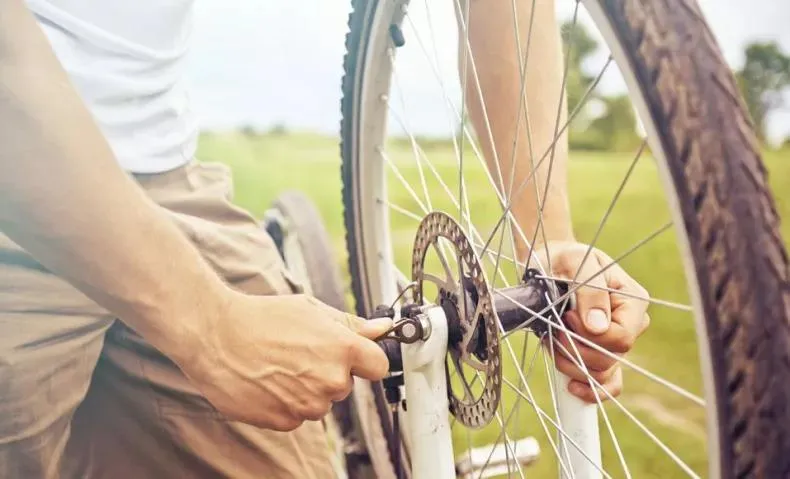 Un homme qui est en train de tenir l'axe d'un pneu de vélo.