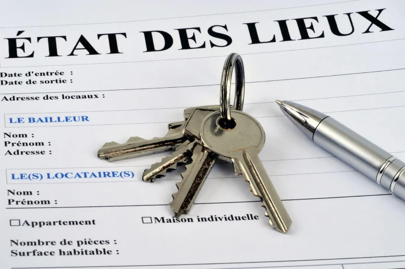 Un formulaire d'état des lieux avec des clés et un stylo posé sur le dessus.