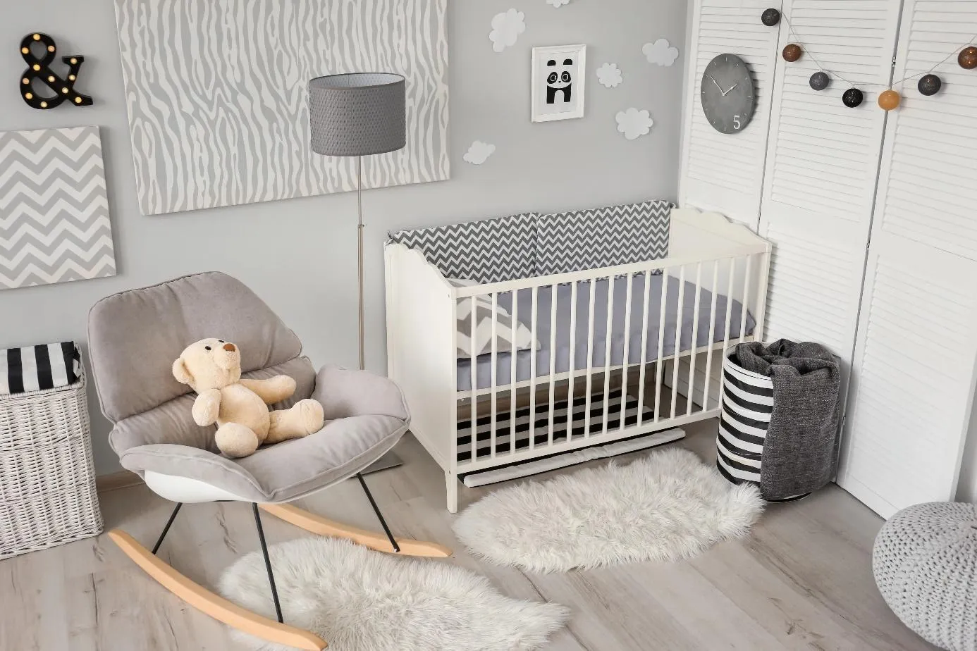 Une chambre de bébé avec un berceau, une chaise et des paniers de rangement dans une couleur grise et blanche.